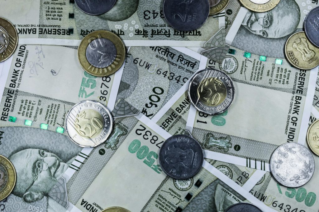 Top view of various Indian rupee banknotes and coins, highlighting financial themes.